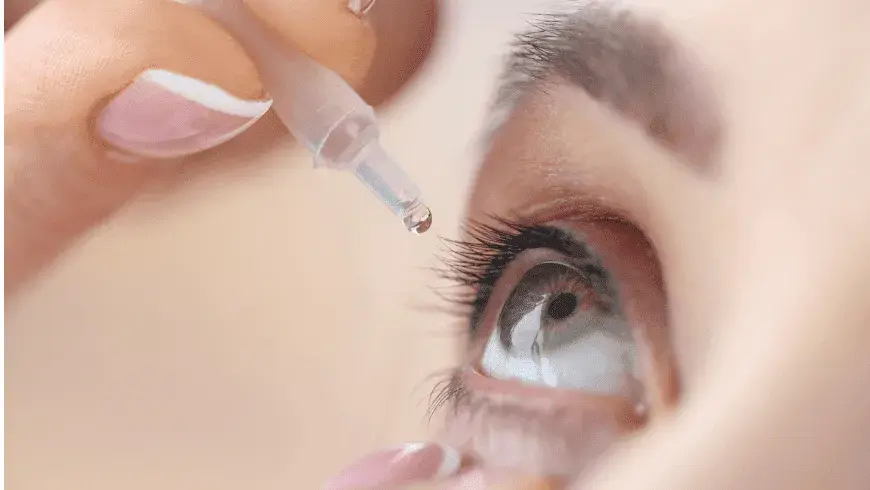Closeup of a person applying eye drops to a large, open eye.