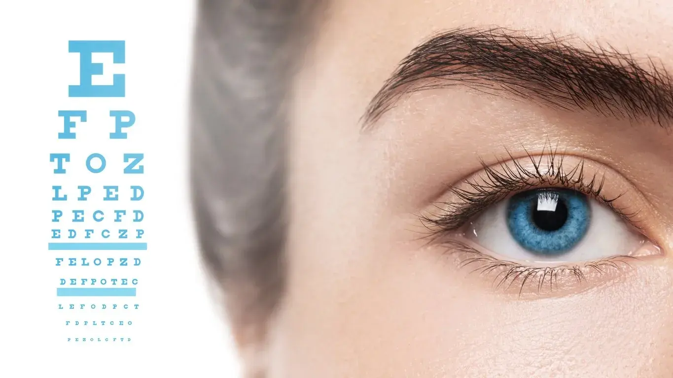Close-up of a blue eye with an eye chart in the background.
