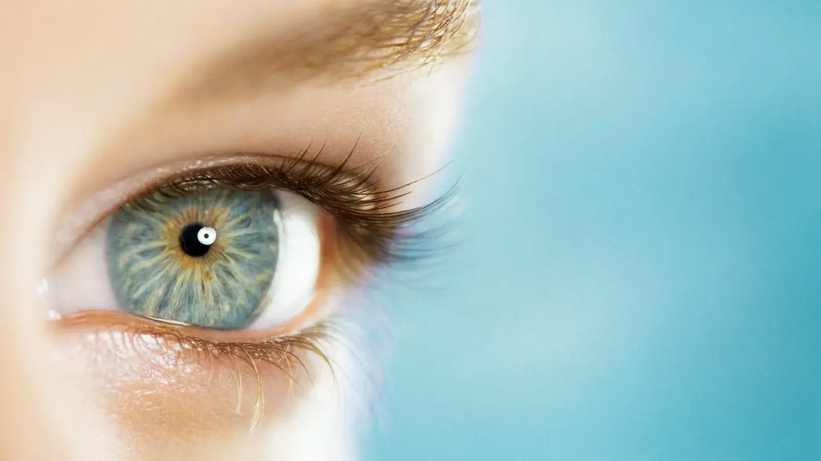 Close-up of a human eye with intricate blue and green iris details.