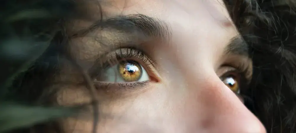 Close-up of a person's brown eyes surrounded by curly hair.