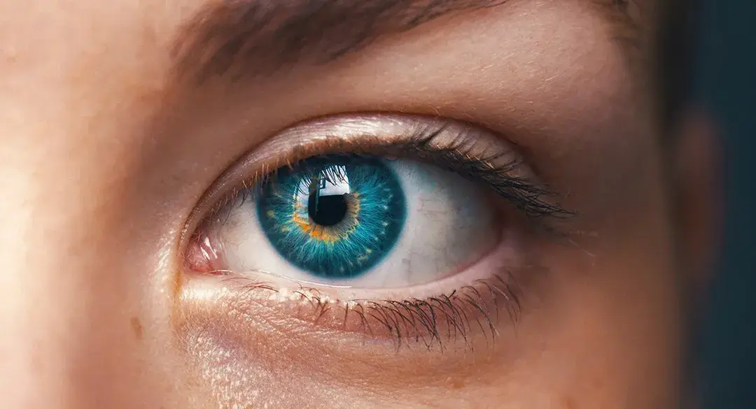 Close-up of a human eye with a vibrant blue iris and intricate details.