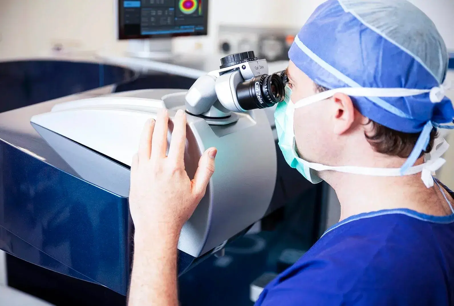 Doctor in surgical attire operating Wavelight laser eye surgery device.