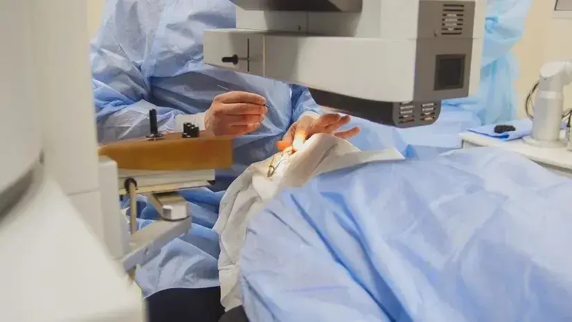 Closeup of a laser surgery procedure with medical staff in blue attire.