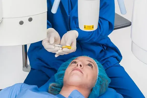 Patient lying down with an injector, preparing for corneal crosslinking procedure.