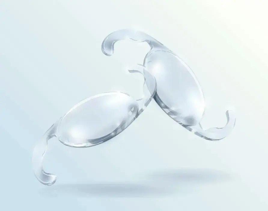 Two clear intraocular lenses displayed against a soft gradient background.