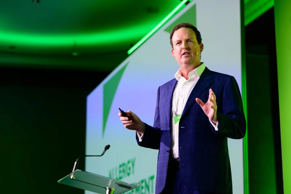 Dr Brendan Cronin speaking on stage, holding a presentation remote and gesturing to the audience